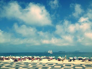 People on beach against cloudy sky