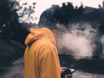 Side view of man holding cigarette against blurred background