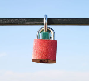 Close-up of padlocks hanging on metal against sky