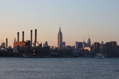 Empire state building and east river against clear sky during sunset in city