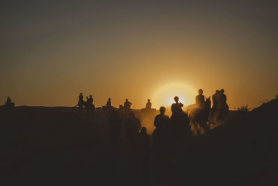 Silhouette people riding horses during sunset