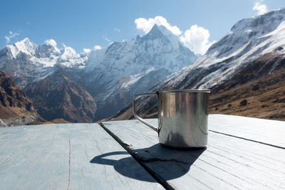 Close-up of mug on table against mountain range