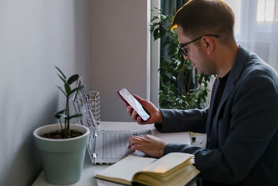 Side view of man using mobile phone at home