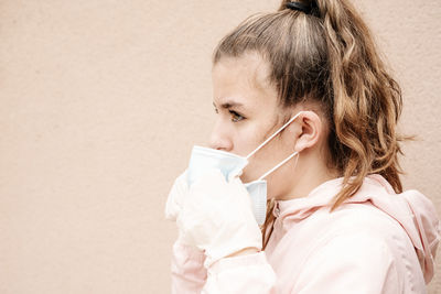 One blonde girl wearing latex gloves and face masks is showing the way she protects herself from coronavirus, bacterias, virus, fungus, etc. she removed mask to take clear breath. horizontal