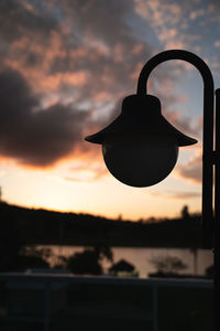 Low angle view of silhouette lighting equipment on field against sky