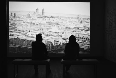 Rear view of man and woman sitting against buildings