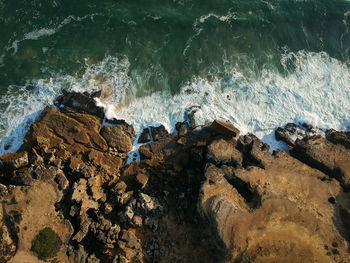 Aerial view of sea waves splashing on rocks