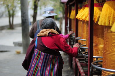 Rear view of people walking by prayer wheels at temple