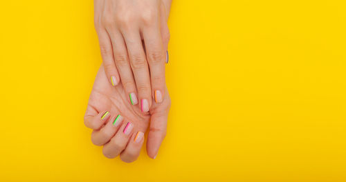 Close-up of woman hand against yellow background