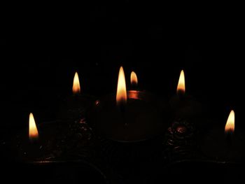 Close-up of burning candles against black background