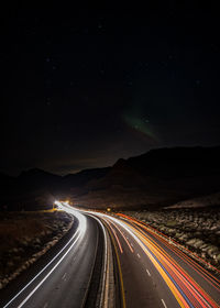 Light trails on road against sky at night