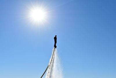 Low angle view of woman against clear sky on sunny day