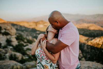 Multiracial couple kissing on top of mountain