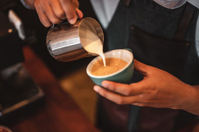 Midsection of barista preparing coffee in cafe