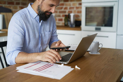 Midsection of businessman using laptop on table