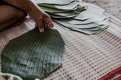 Midsection of man holding banana leaf while sitting on mat