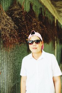 Portrait of smiling man wearing sunglasses standing against trees