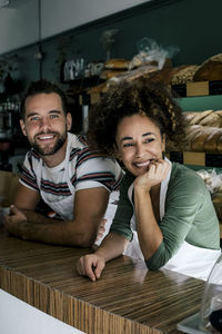 Smiling female owner with hand on chin by male colleague in bakery