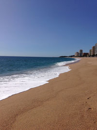 Scenic view of beach against clear blue sky