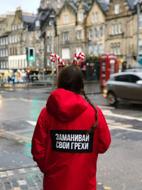 Rear view of woman standing on street in city