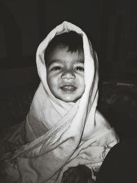 Portrait of cute baby boy wrapped in blanket at home