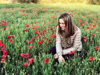 Woman standing by poppy flowers on field