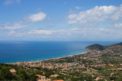 Scenic view of sea by townscape against sky