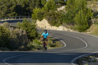 A man, standing up on his pedals, bikes uphill in costa blanca