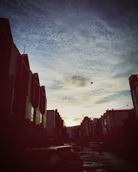 Street amidst buildings against sky during sunset