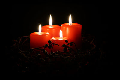 Close-up of lit candles over black background