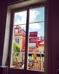 Buildings against sky seen through glass window