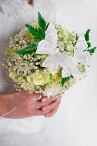 Midsection of bride holding butterflies on bouquet