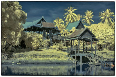 Gazebo by lake and building against sky