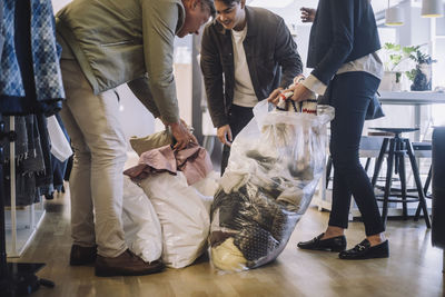 Fashion designers removing recycled clothes from plastic bags at workshop