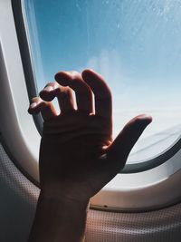 Close-up of cropped hand by airplane window