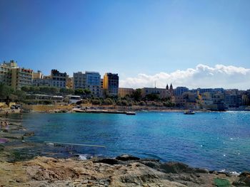 Scenic view of sea and cityscape against clear blue sky