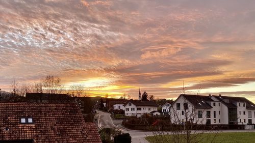 Houses and buildings against sky during sunset