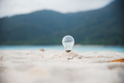 Close-up of light bulb in sand at beach