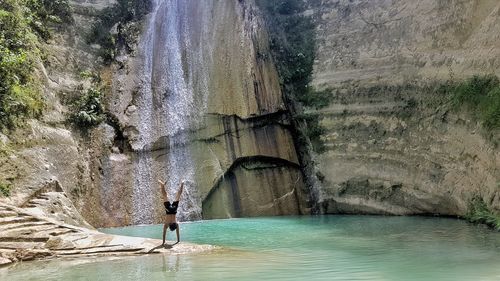 Man practicing handstand against waterfall