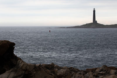 Lighthouse by sea against sky