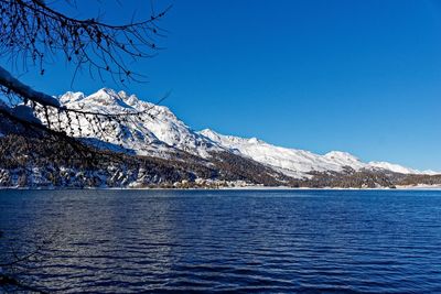 Scenic view of lake and snowcapped mountains against clear blue sky