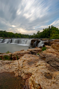 Scenic view of waterfall against sky