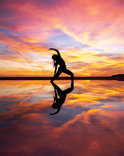 Silhouette woman on sea against sky during sunset. yoga pose