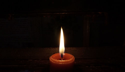 Close-up of lit candle in darkroom