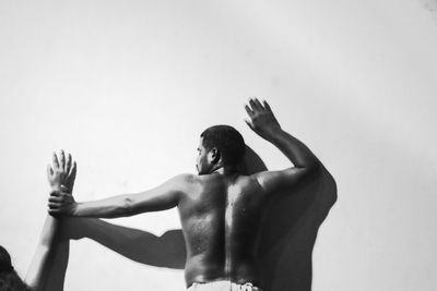 Low angle view of shirtless young woman against white background