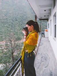 Side view of woman photographing with camera