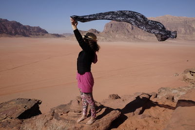 Full length of woman holding sarong in desert