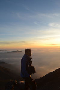 Man standing on mountain against sky during sunset