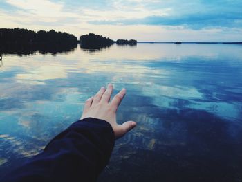 Close-up of hand against calm lake