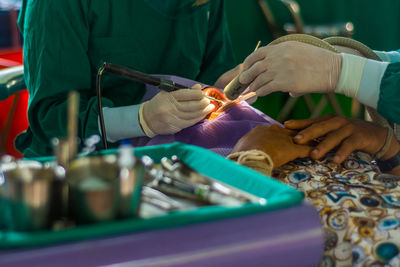 Midsection of male dentist operating patient in hospital